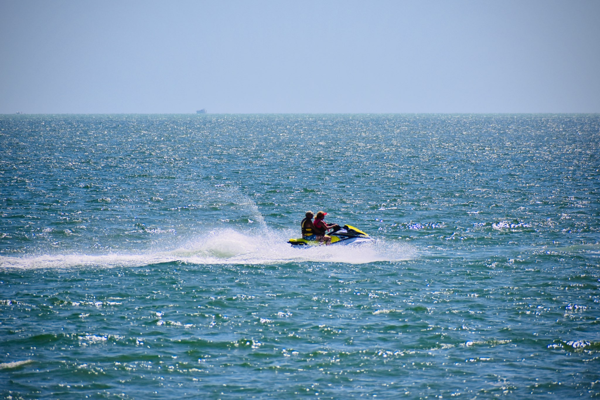 Two riders on a jetski over clear turquoise water